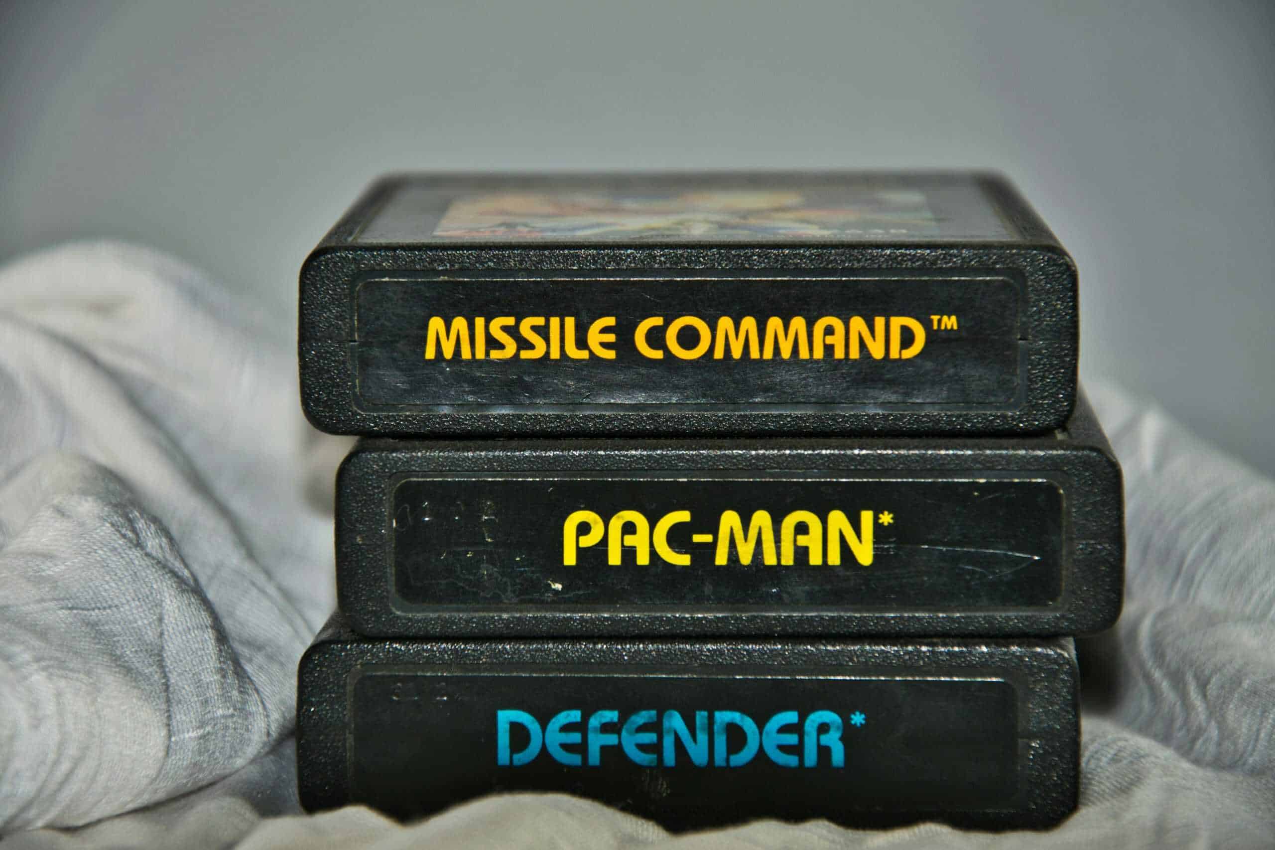 Close-up of vintage Atari game cartridges for Missile Command, Pac-Man, and Defender.